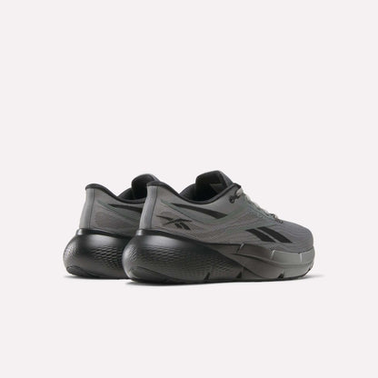 A pair of Reebok Men's Zignition Running Shoes in gray, featuring thick sculpted black soles, shown from a rear and side angle against a plain light background.