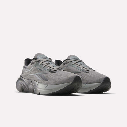 A pair of Reebok Men's Zignition Running Shoes with mesh uppers, thick textured soles, and silver accents is shown in gray on a plain white background.