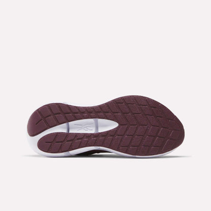The image displays the sole of Reebok Women's Zignition Running Shoes, highlighting a maroon tread with textured grip and a white oval cutout near the arch, all shown from below against a plain white background.