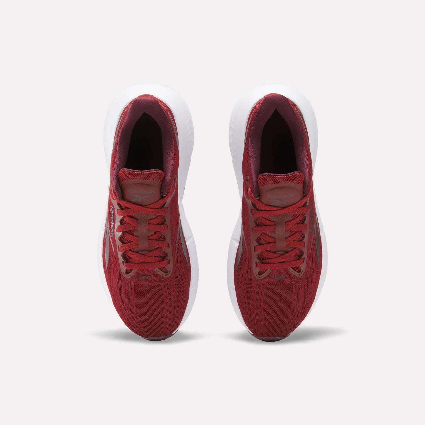 Top view of Reebok Women's Zignition Running Shoes with red mesh uppers and white soles, side by side on a light background. These cushioned running shoes are laced up and ready for action.