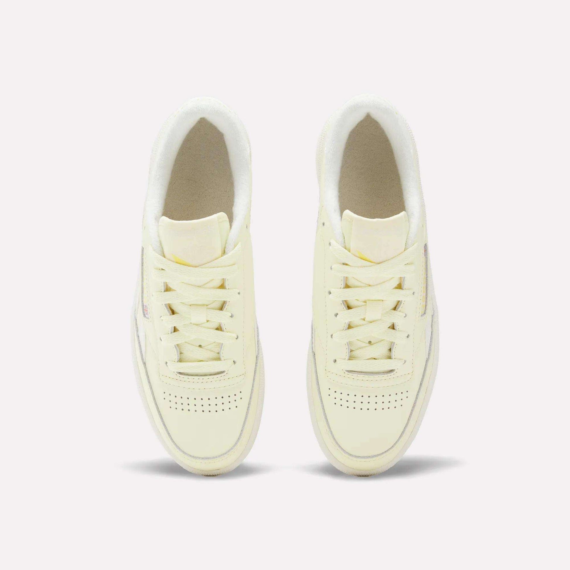 A pair of off-white Women's Club C Revenge Shoes by Reebok with laces, viewed from above on a plain light background, highlights the timeless appeal of vintage court style.