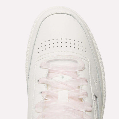 Top view of Women's Club C 85 Vintage Shoes by Reebok in white with light pink laces and toe perforations for ventilation, photographed on a plain white background.