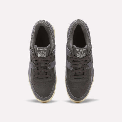 Top view of a pair of dark gray Reebok Workout Plus Shoes featuring laces, white Reebok logos on the tongues, a suede upper, perforated toes, and light outsoles on a plain white background.