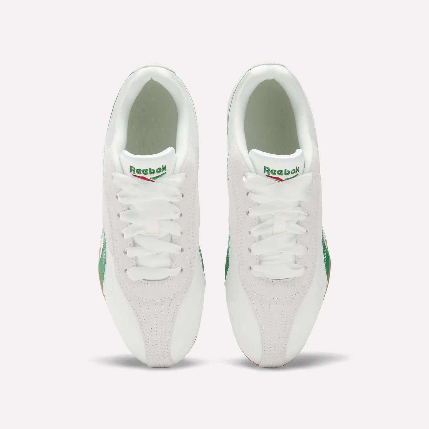 Top view of Women's Ultra Lo Shoes by Reebok: white sneakers with green accents and gum soles, placed side by side on a light background, featuring the visible Reebok logo on each tongue.