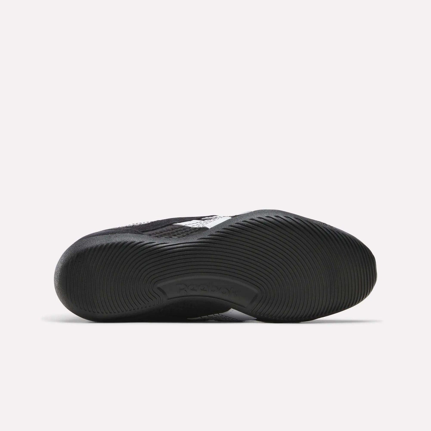 The image shows the black rubber sole of a Reebok Women's Ultra Lo Mary Jane Shoe from below, featuring a textured wavy tread and an embossed Reebok logo near the arch on a plain white background.