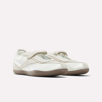 The Reebok Women's Ultra Lo Mary Jane Shoes feature a white and beige low-profile runner design with Velcro straps and subtle stitching details, displayed on a plain light background.