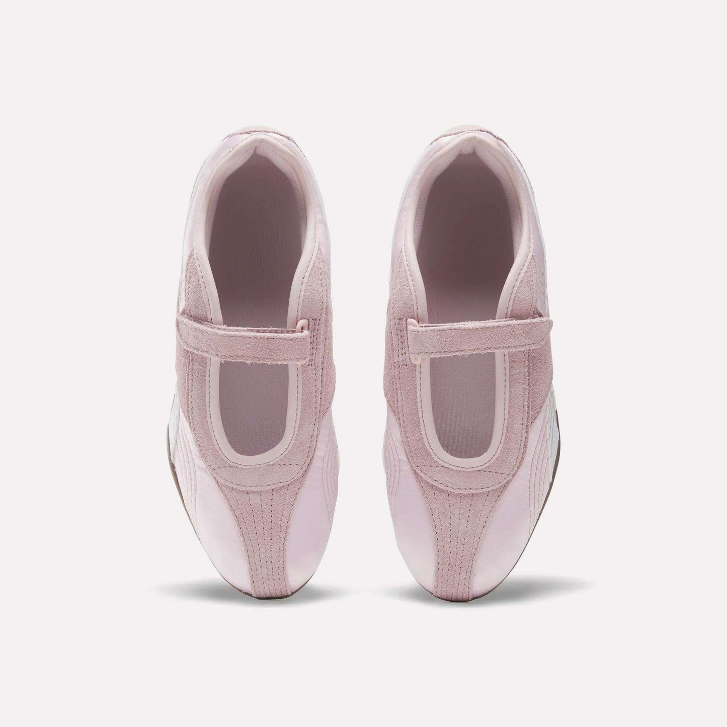 A pair of Women's Ultra Lo Mary Jane Shoes by Reebok in light pink with velcro straps, styled as low-profile runners, shown from above on a plain white background.