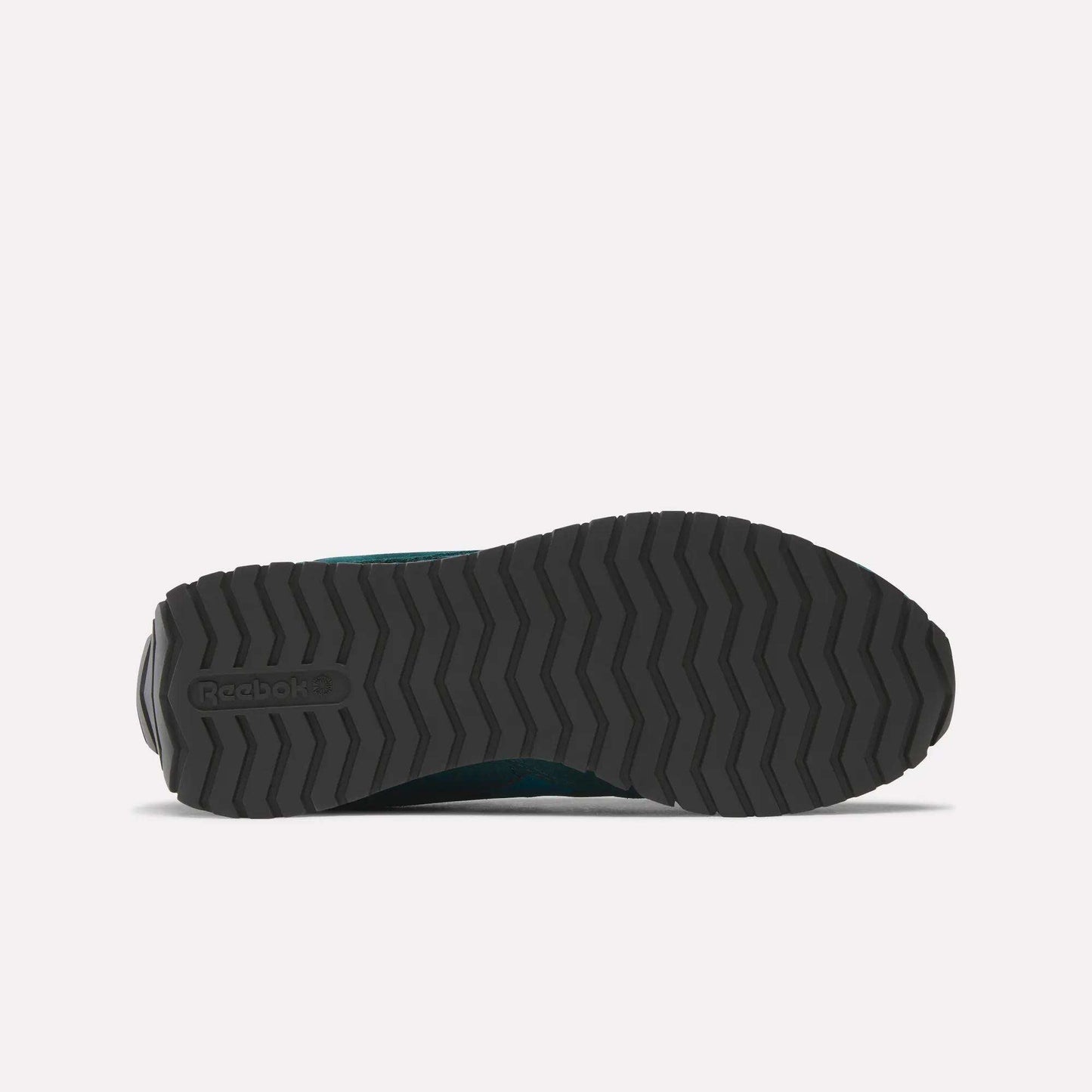 The image shows the black, textured rubber outsole of the Women's Classic AZ Shoes by Reebok, featuring a zigzag tread and an embossed Reebok logo on the left side, emphasizing its retro running design against a plain background.
