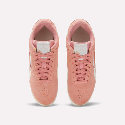 The Women's Freestyle Lo Shoes by Reebok feature a pink upper with white soles and side stripes, offering classic retro sneaker style. Displayed from above on a plain white background, they're the perfect addition to any look.