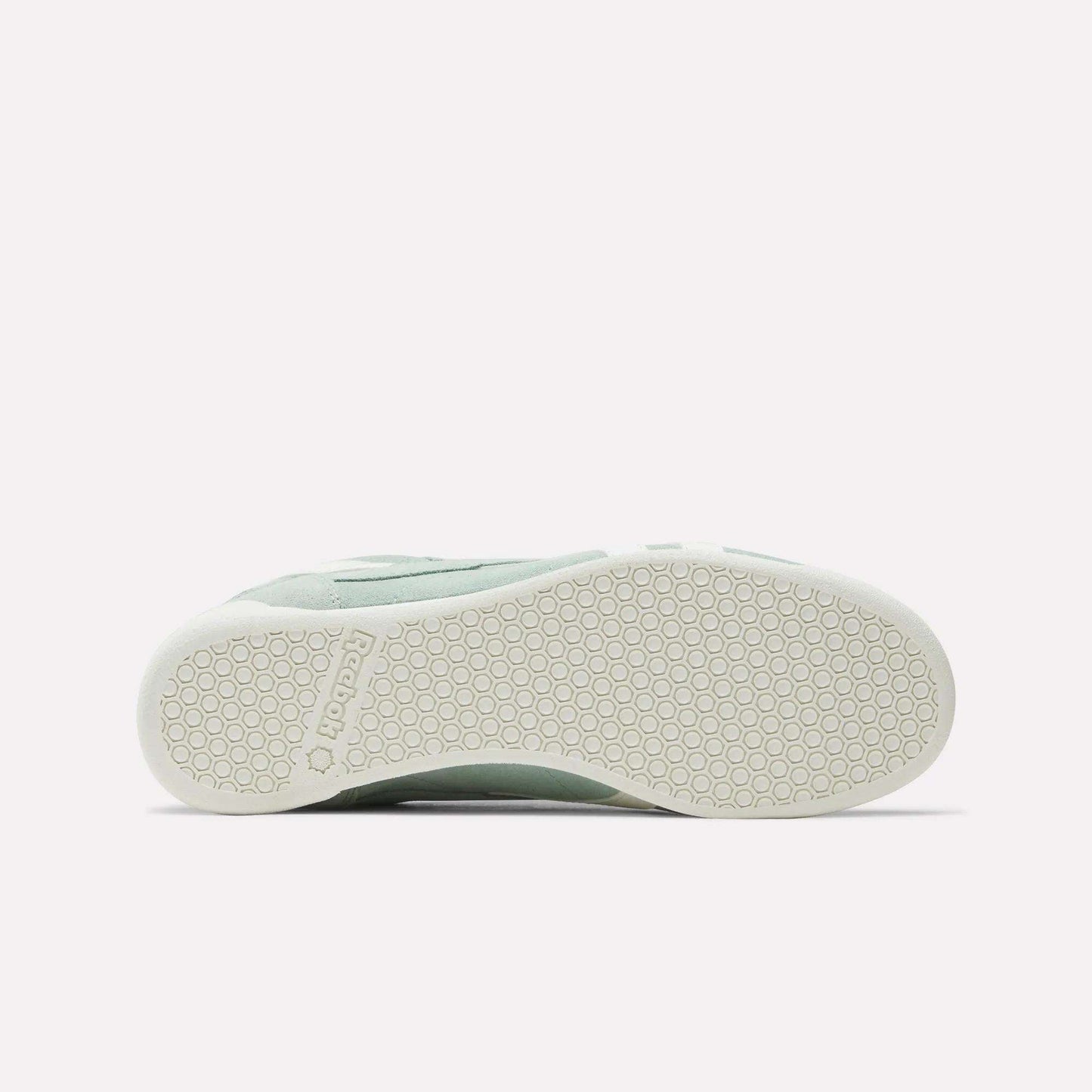 Bottom view of the Women's Freestyle Lo Shoes by Reebok in light green, showing a white rubber sole with a hexagonal pattern and embossed Reebok logo near the heel—ideal for retro sneaker enthusiasts.