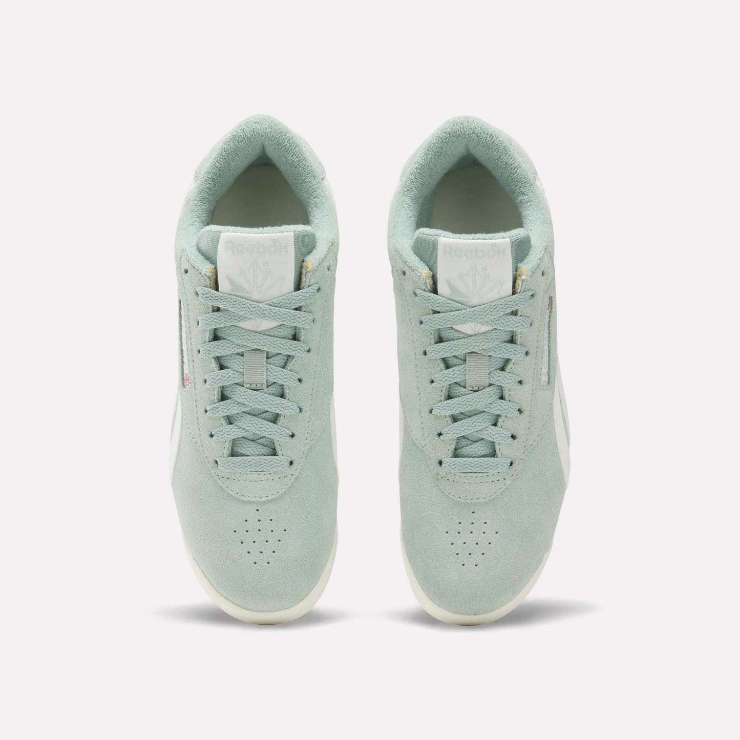 A pair of Women's Freestyle Lo Shoes by Reebok in light green suede are shown from above, displaying the tops, laces, tongues with Reebok logos, and placed side by side on a plain white background.