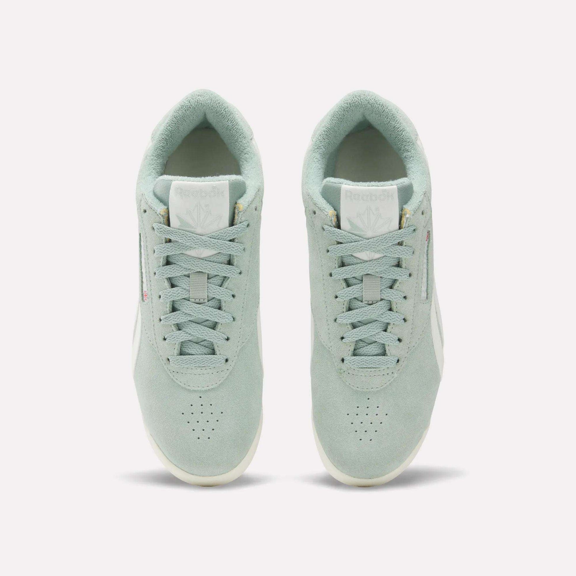 A pair of Women's Freestyle Lo Shoes by Reebok in light green suede are shown from above, displaying the tops, laces, tongues with Reebok logos, and placed side by side on a plain white background.
