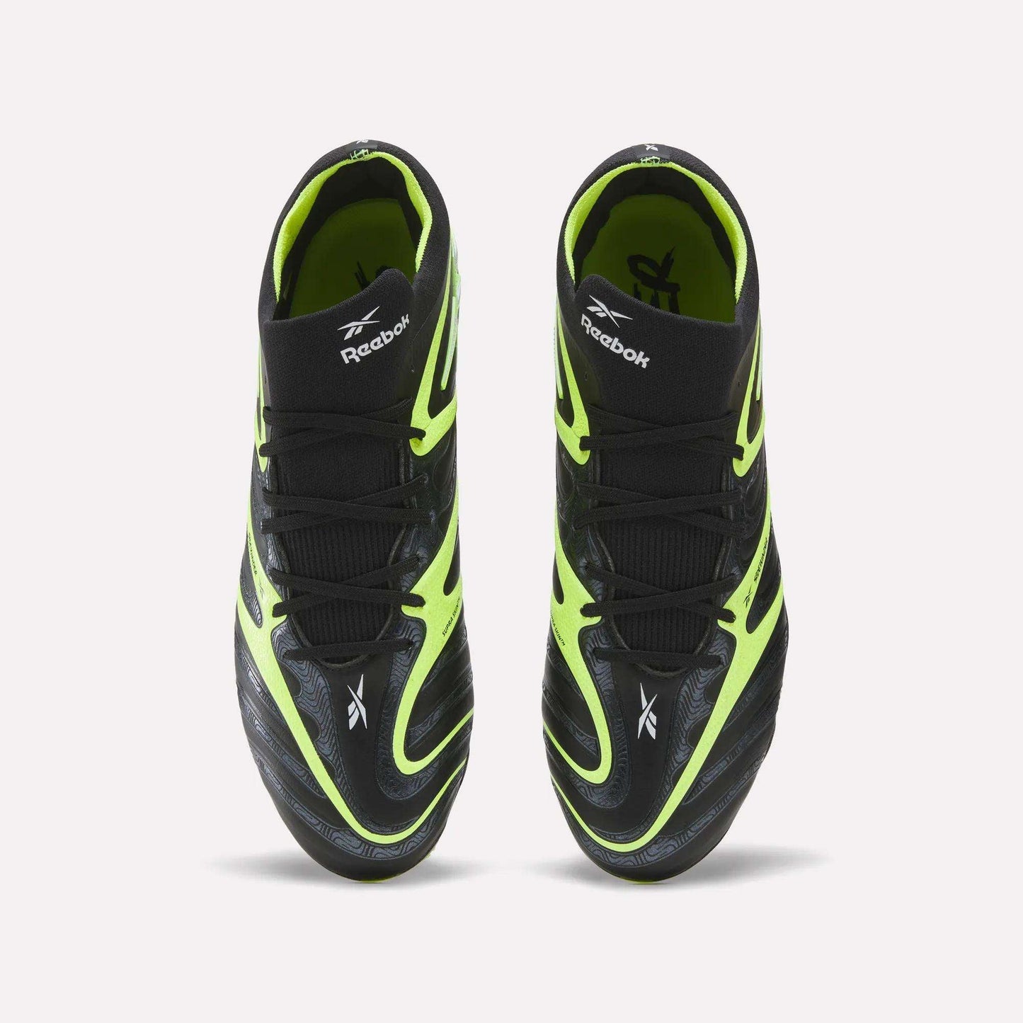 A pair of Reebok Sidewinder 26 Elite FG Cleats, shown from above, with black uppers, neon yellow accents, and white logos—designed for firm ground play and superior ball control.