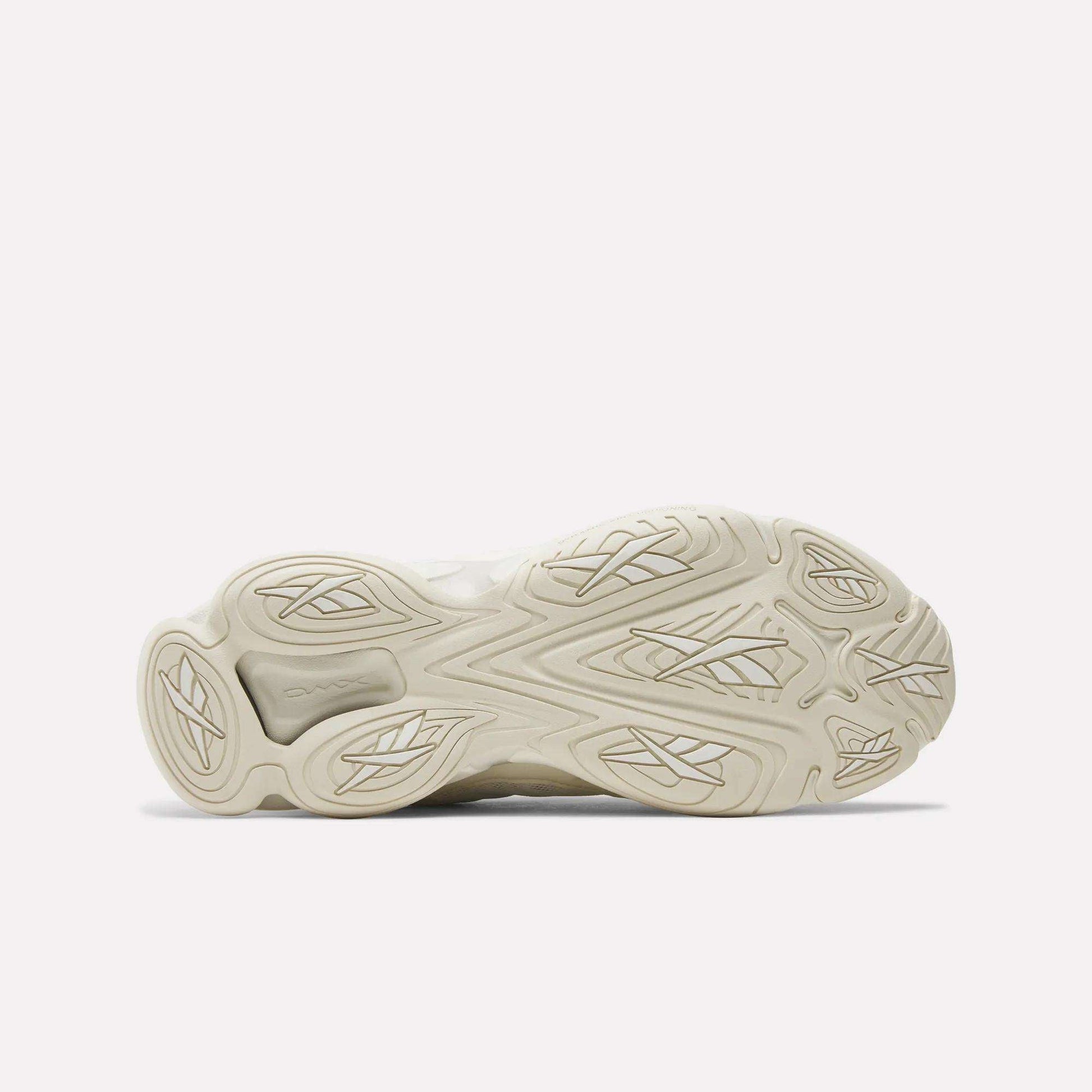 The image displays the outsole of Reebok's DMX Series 3000 Shoes facing up, in light beige with wavy and geometric tread patterns for grip. The intricate design emphasizes comfort, with visible adiPRENE branding on one section.