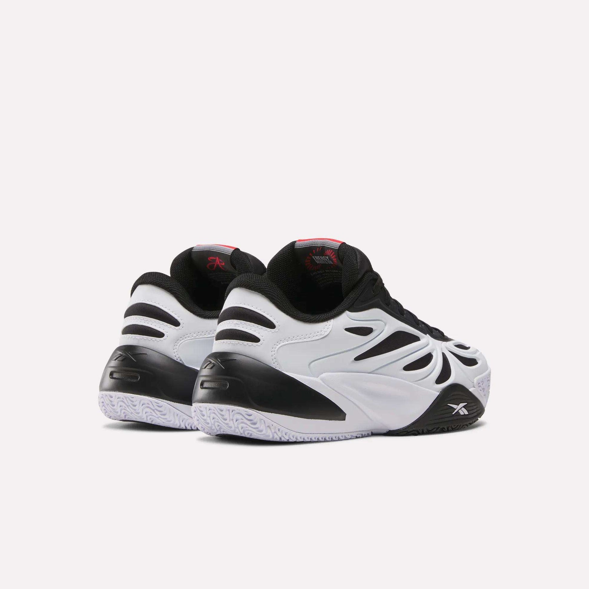 The Reebok Angel Reese 1 Shoes for big kids, featuring black and white wavy designs, black accents, and textured white soles, are displayed from the back and side on a plain light background.