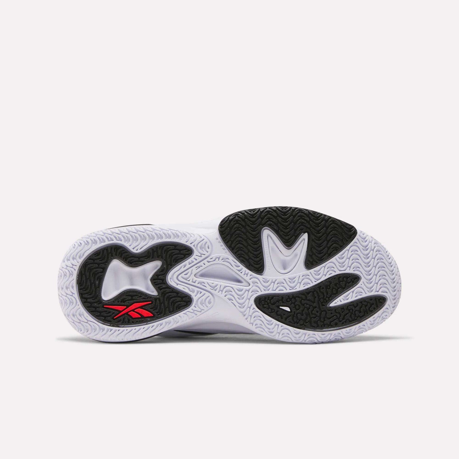 The image shows the sole of the Reebok Angel Reese 1 Shoes - Big Kids with a white base, black grip sections, and a small red Reebok logo by the heel. Wavy and textured tread lines offer great traction—ideal for kids’ basketball.