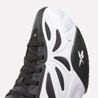 Close-up of the toe and side of the Reebok Angel Reese 1 Shoes - Big Kids, a black and white performance basketball sneaker with a textured sole, geometric design, black laces, and two white logos inspired by Angel Reese.