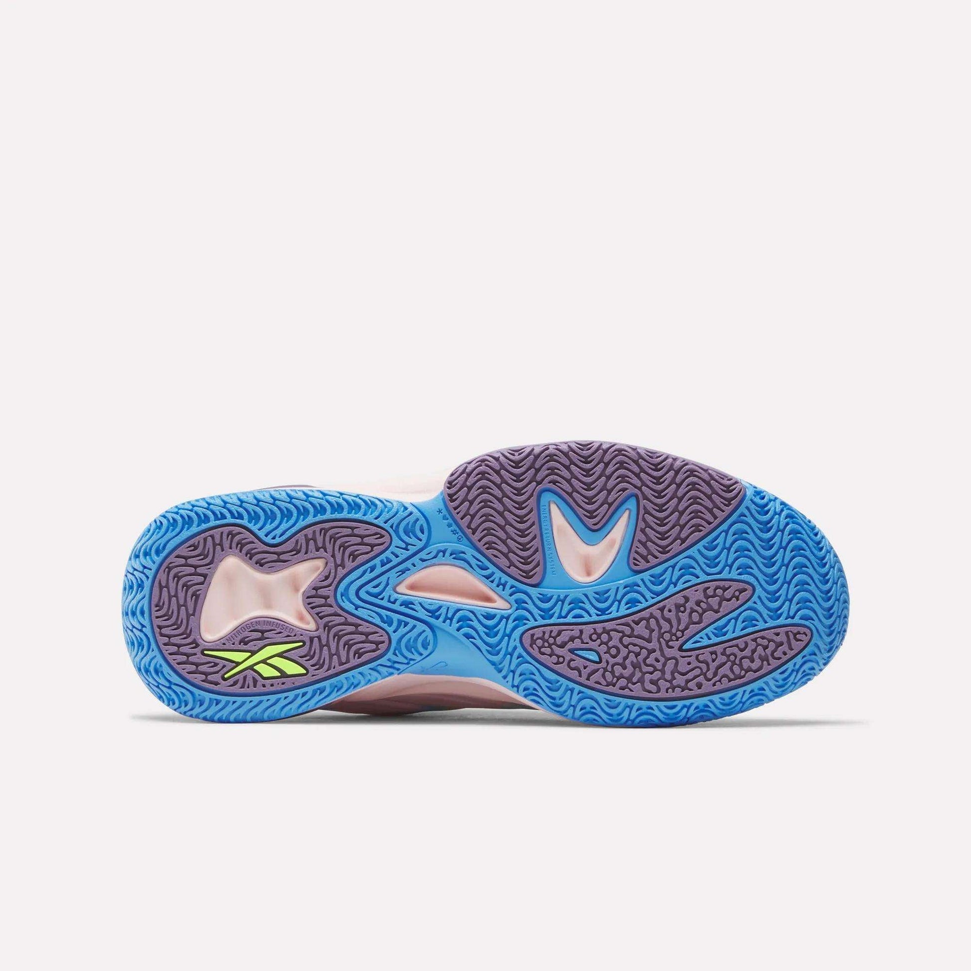 The image shows the outsole of the Reebok Angel Reese 1 Shoes for Big Kids, featuring an intricate wavy tread in blue and purple with a small neon green Reebok logo by the heel. The background is plain white.