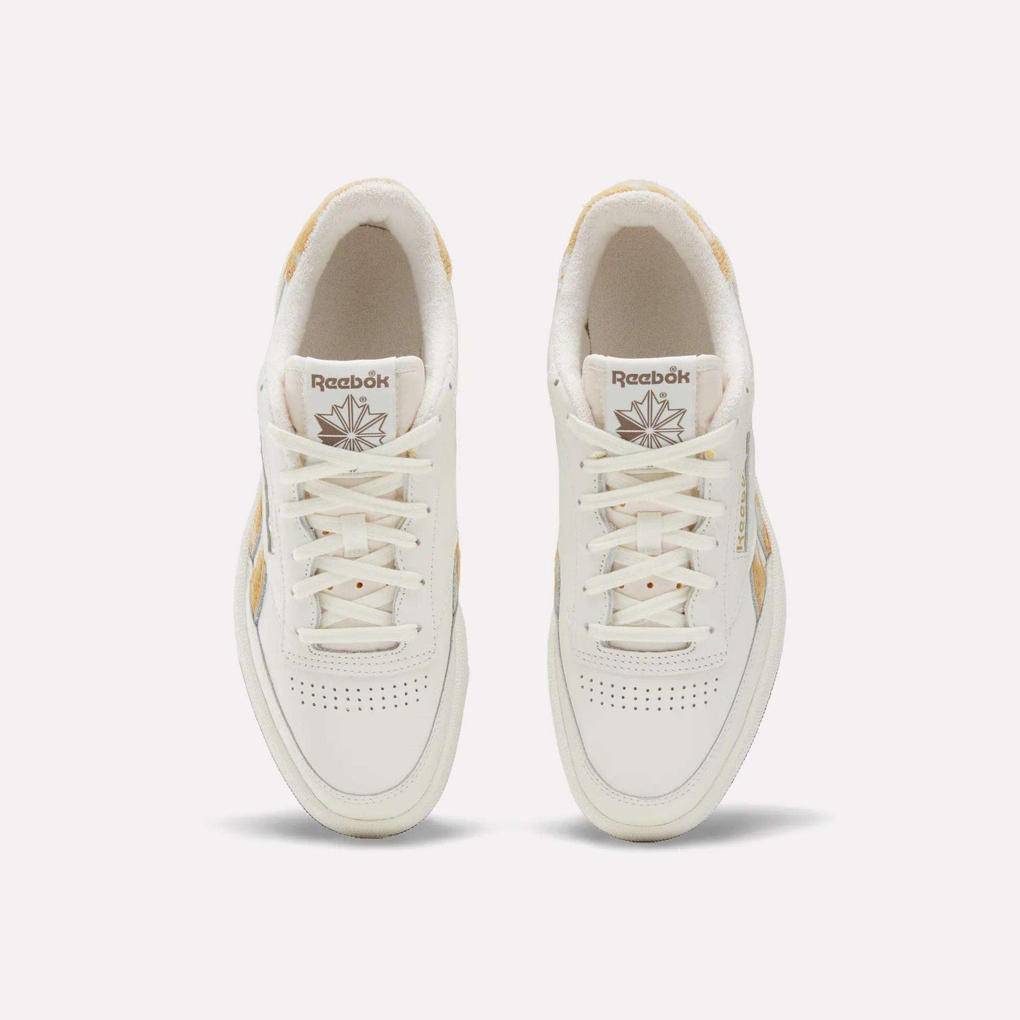 Top view of a pair of Reebok Club C Revenge Vintage Shoes with beige accents, white laces, and perforated detailing on the toes, featuring a classic leather upper. These tennis-inspired sneakers are displayed on a plain light background.