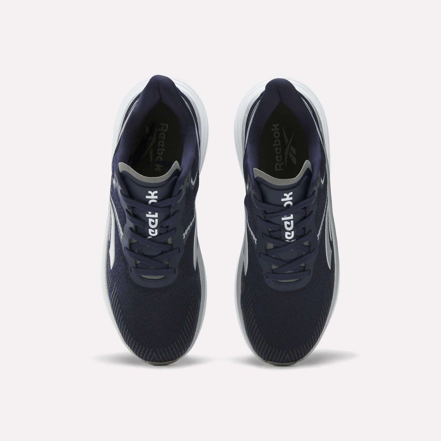 Top view of a pair of Reebok Men's Viva Speed Shoes in navy blue, featuring breathable material, white soles, and white Reebok logos on the tongues, placed side by side on a plain white background.