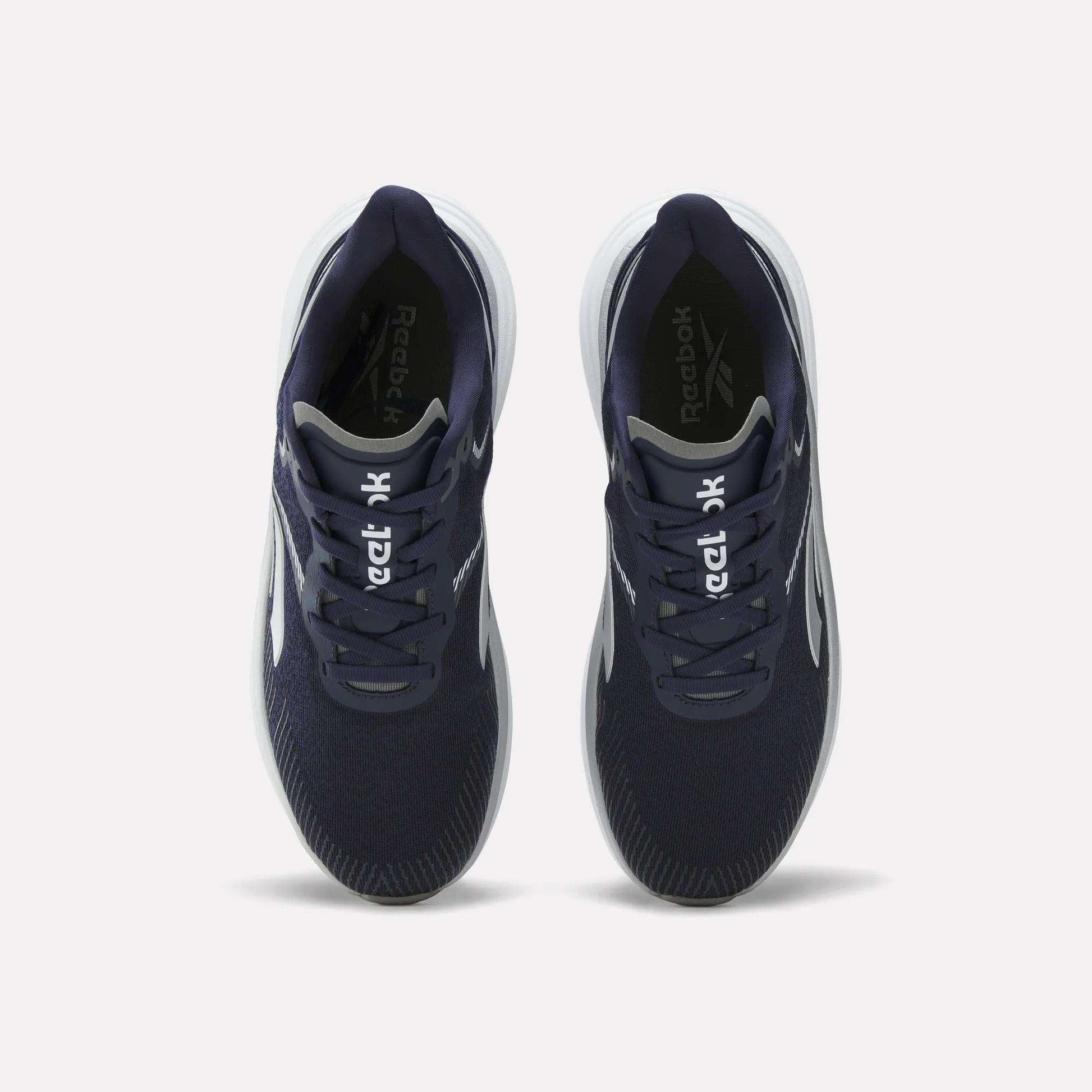 Top view of a pair of Reebok Men's Viva Speed Shoes in navy blue, featuring breathable material, white soles, and white Reebok logos on the tongues, placed side by side on a plain white background.