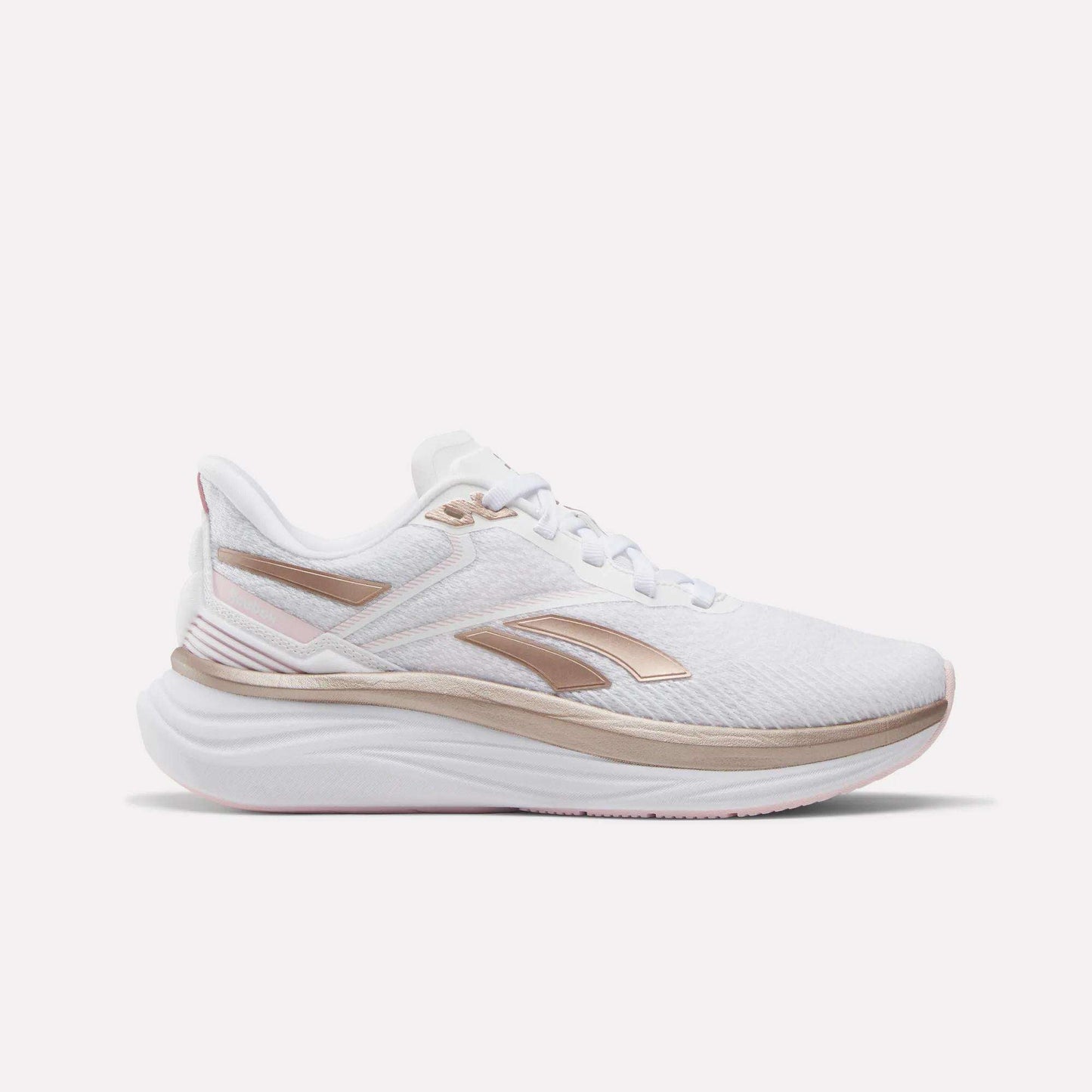 The Reebok Women's Viva Speed Shoes feature a white design with metallic rose gold accents and a thick, cushioned sole, displayed in a side profile against a plain white background.