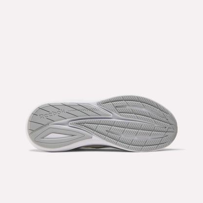 The image displays the sole of Reebok Men's Viva Speed Shoes in white and gray, featuring textured tread patterns, grooves for traction, and the Reebok logo on the left side, emphasizing the shoes’ enhanced cushioning.