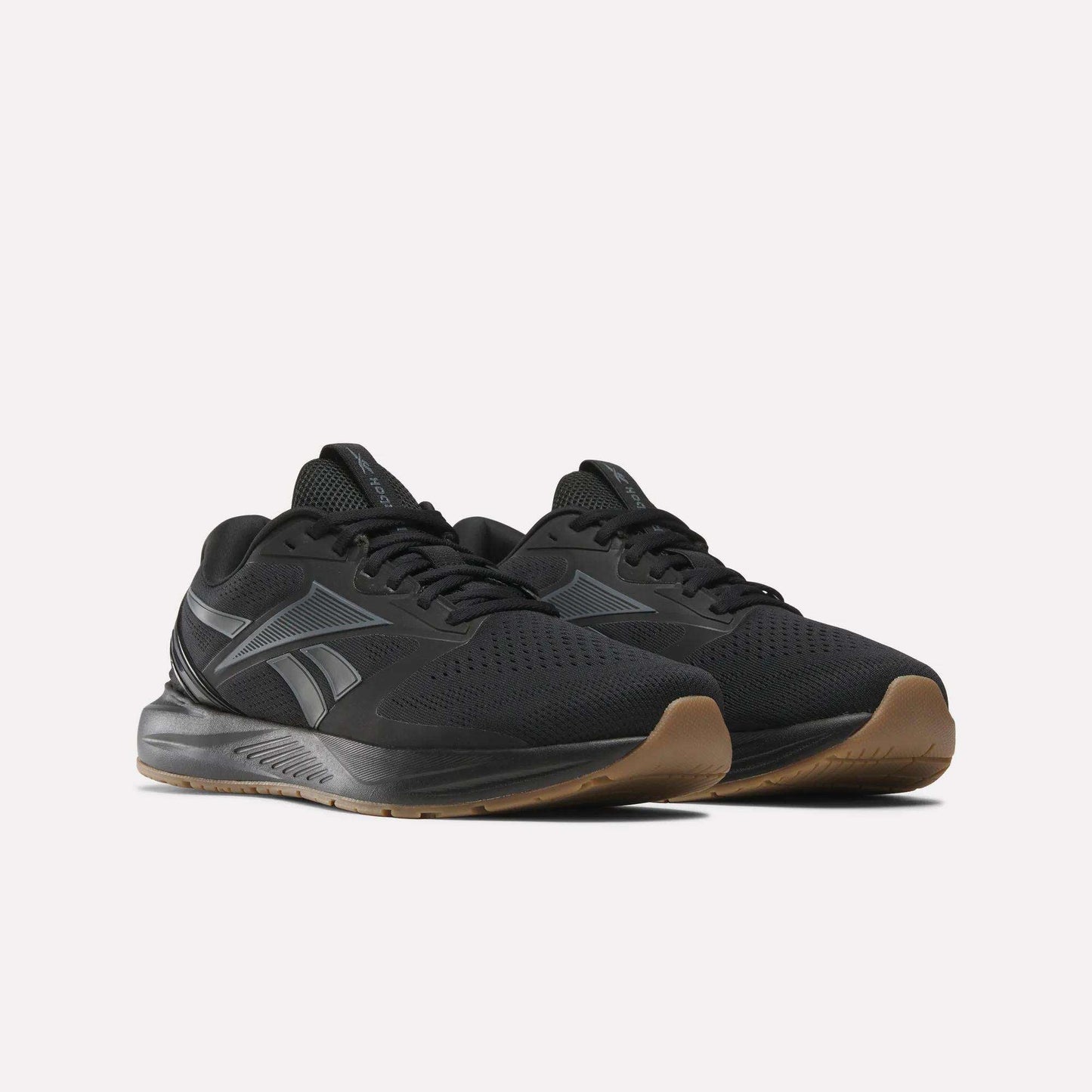 The Reebok Men's Nanoflex Trainer 2 Shoes are black with gray accents and a brown rubber sole, shown on a white background. They feature a mesh upper and the Reebok logo on the side, making them ideal for workouts.