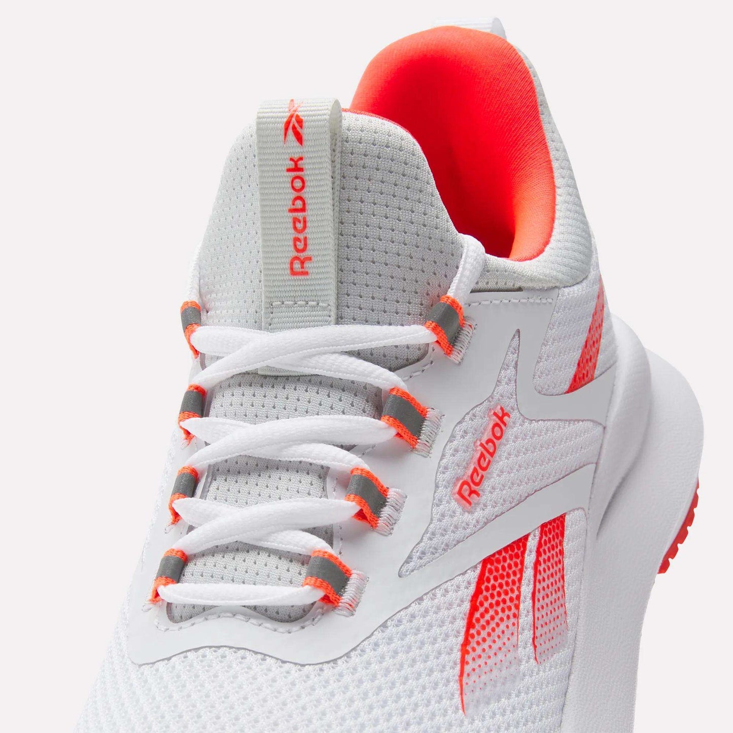 A close-up of the Reebok Women's Cityride 2 Running Shoes in white with orange accents, mesh upper, white laces with orange eyelets, Reebok logo on tongue and side, and plush FuelFoam cushioning for comfort.