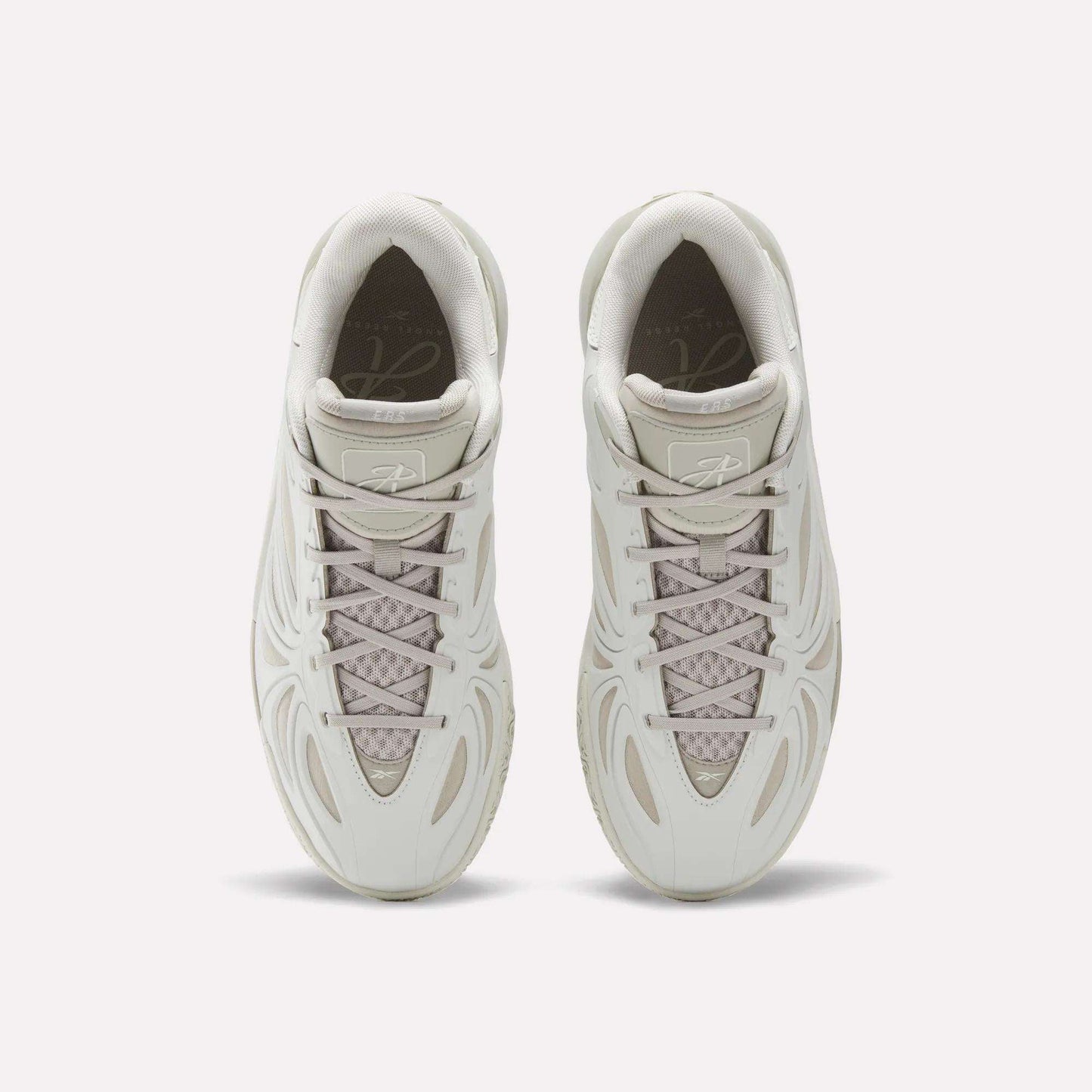 Top view of the Reebok Angel Reese 1 Basketball Shoes in light beige, featuring wavy line designs, mesh tongue detail, and neatly tied laces—these performance sneakers with Energy Return System are displayed side by side on a white background.