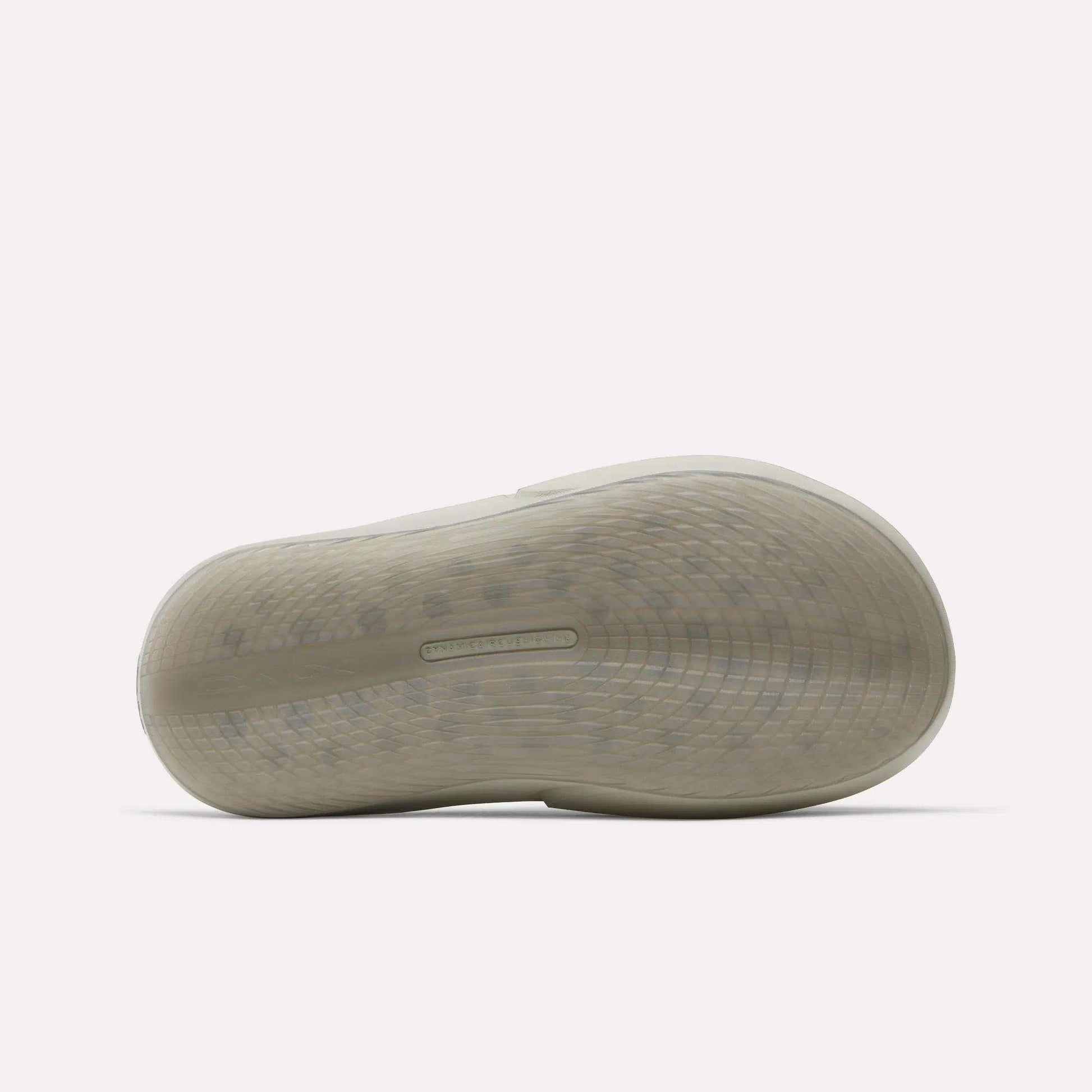 The image shows the bottom view of a Reebok DMX Recovery Mules sole, featuring molded EVA construction with a grid-like textured pattern and a rectangular panel in the center. The background is plain white.