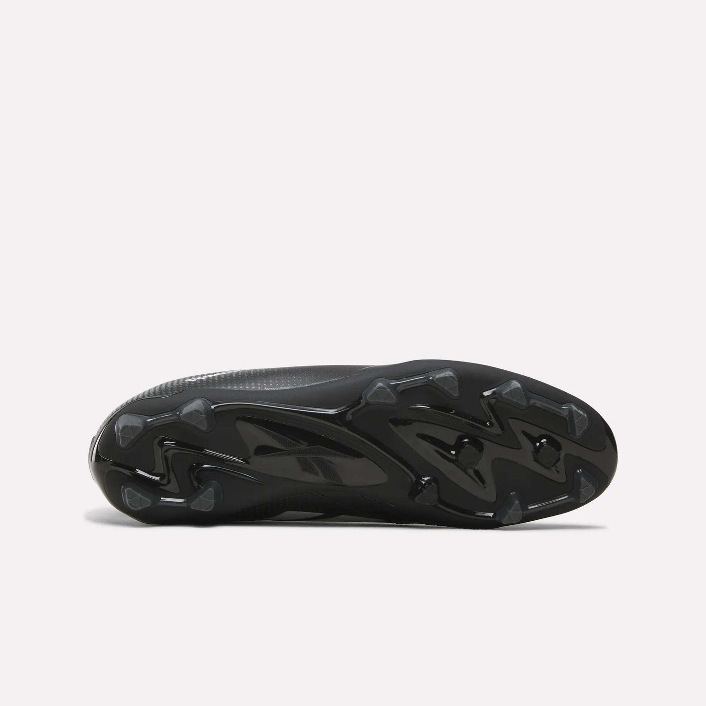 The image displays the black, textured sole of the Reebok Strike Multi Ground Soccer Cleats, featuring molded studs for turf traction, as seen from the bottom against a plain white background.