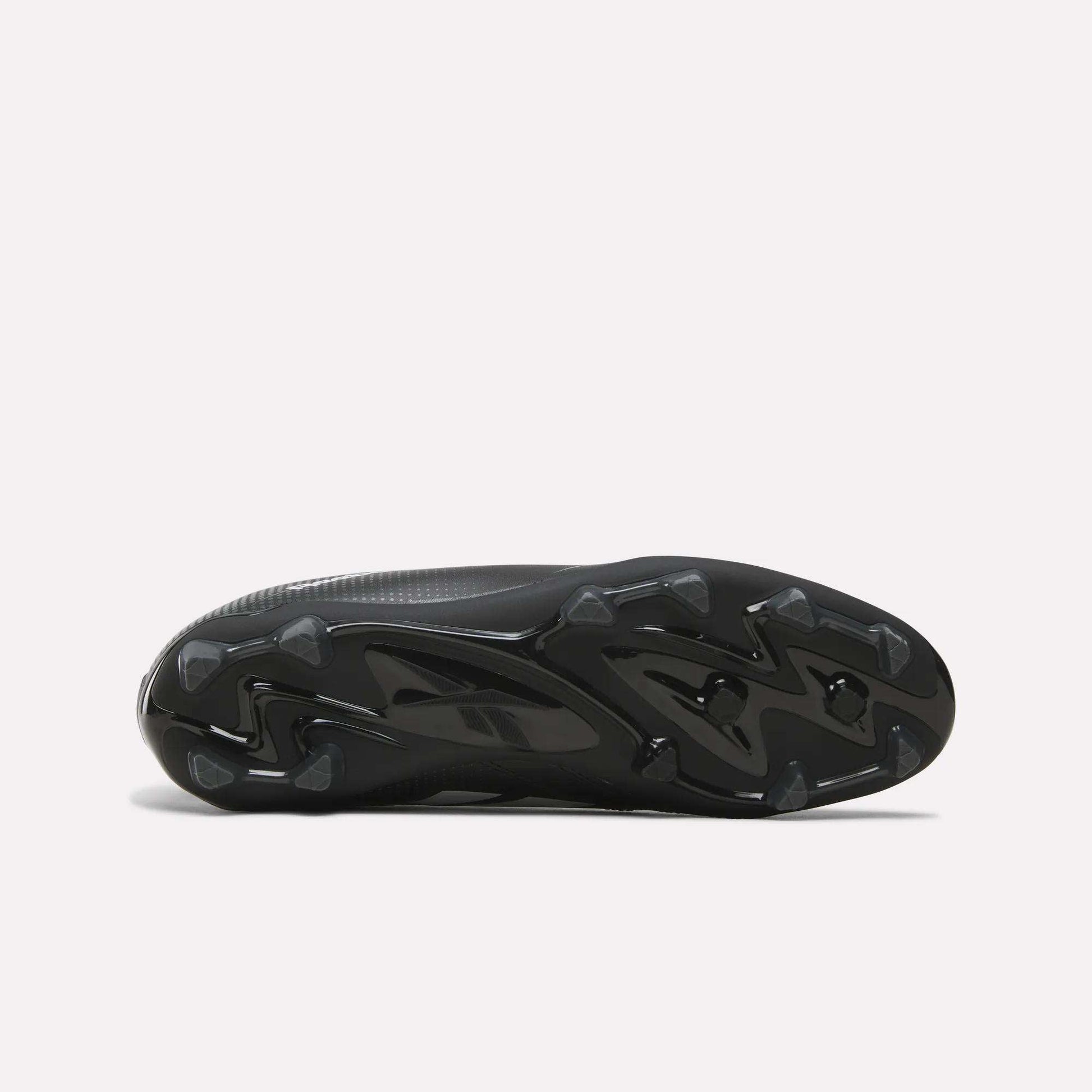 The image displays the black, textured sole of the Reebok Strike Multi Ground Soccer Cleats, featuring molded studs for turf traction, as seen from the bottom against a plain white background.