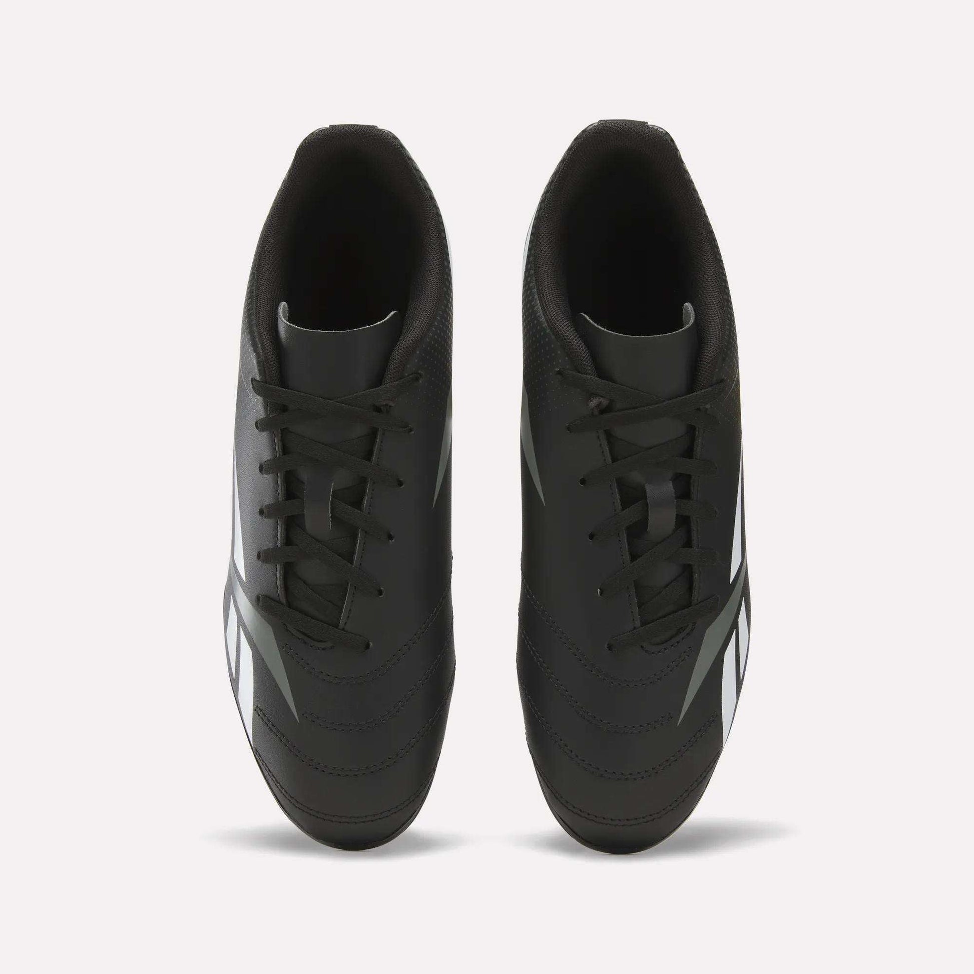 Top view of the Reebok Strike Multi Ground Soccer Cleats in black, featuring white side accents, black laces, and a dark inner lining, showcased on a plain white background—ideal soccer shoes for turf surfaces.