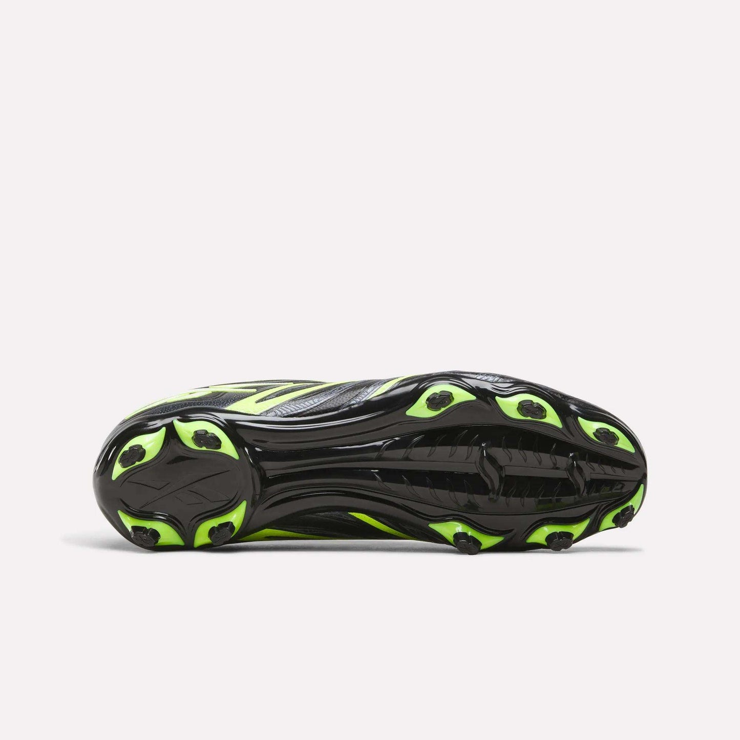 The image shows the sole of the Reebok Sidewinder 26 League FG Cleats for big kids, featuring a black base with neon yellow accents and several firm ground studs for dependable traction on the field.
