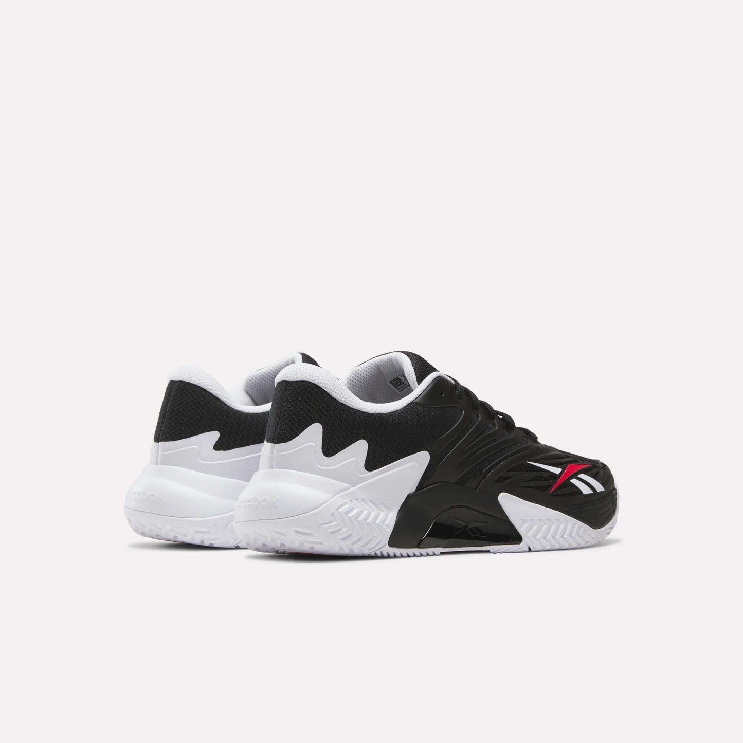 The Reebok Phase EVO Tennis Shoes feature black uppers, wavy white midsoles for responsive rebound, and a red and white Reebok logo on the side. Shown against a plain white background.