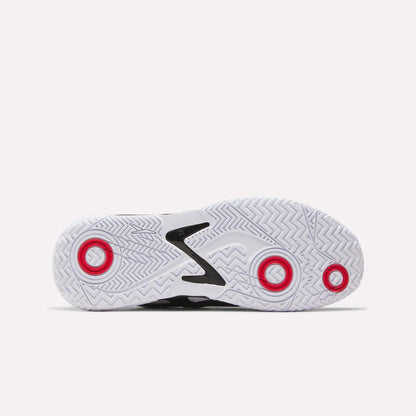 Bottom view of a white Reebok Phase EVO Tennis Shoe sole featuring a zigzag tread and three circular red accents—at the heel, ball, and toe—showcasing durable construction and responsive rebound against a plain light background.
