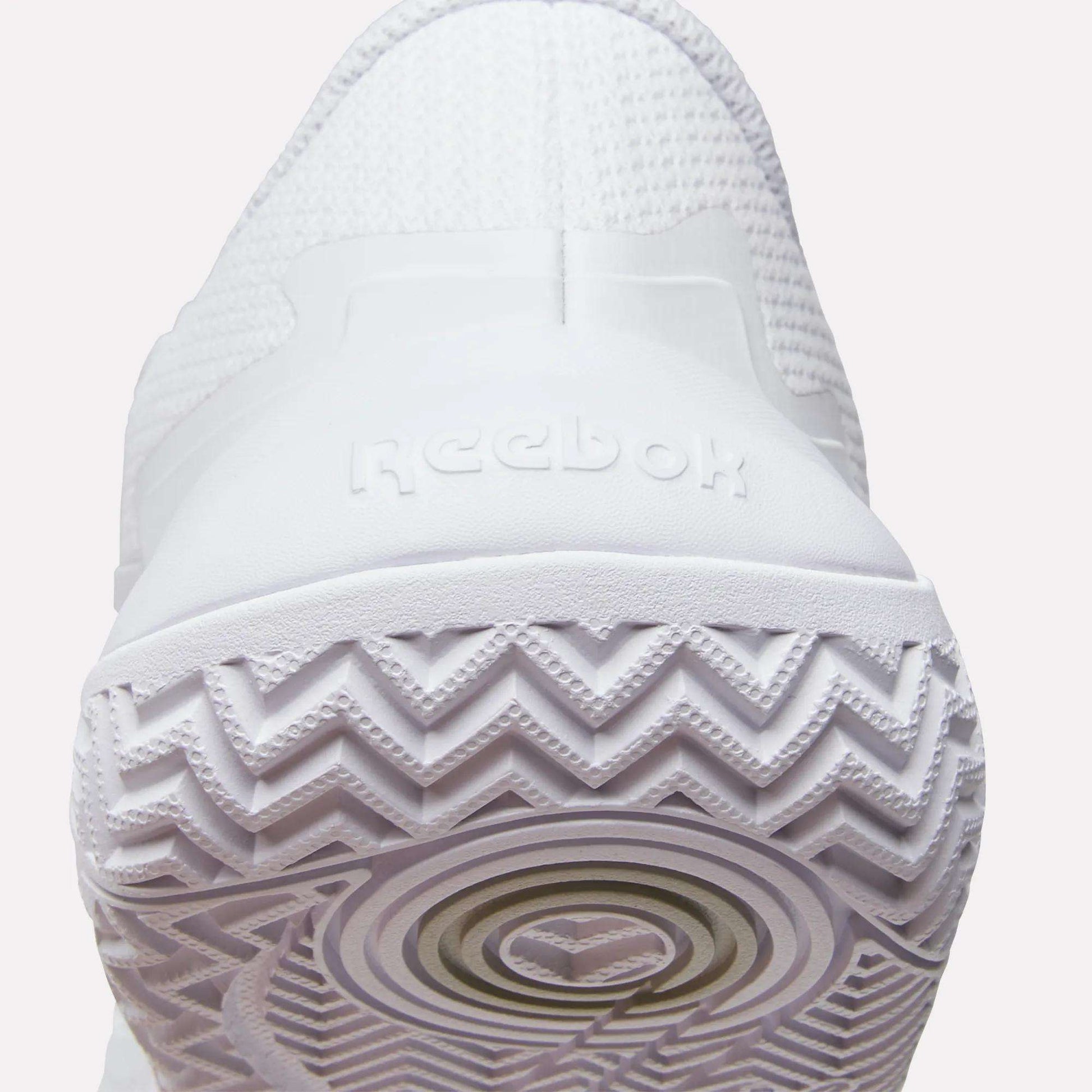 Close-up of the heel and sole of Reebok Women's Phase Evo Tennis Shoes, featuring the Reebok logo on the back and a zigzag tread pattern for durable performance.