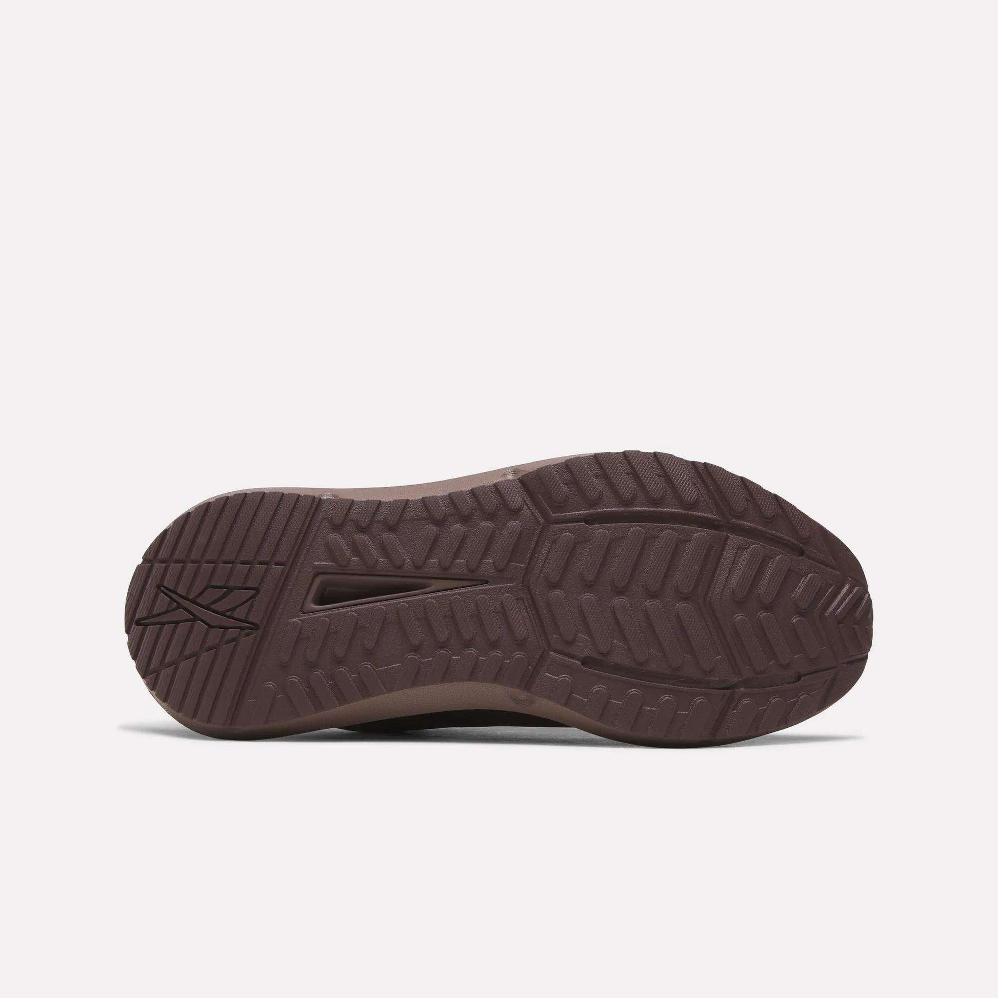 The image shows the sole of a brown Reebok Women's Cityride 2 Running Shoe with a textured tread, angular and curved grooves, FuelFoam cushioning, and the Reebok logo near the heel on a plain white background.