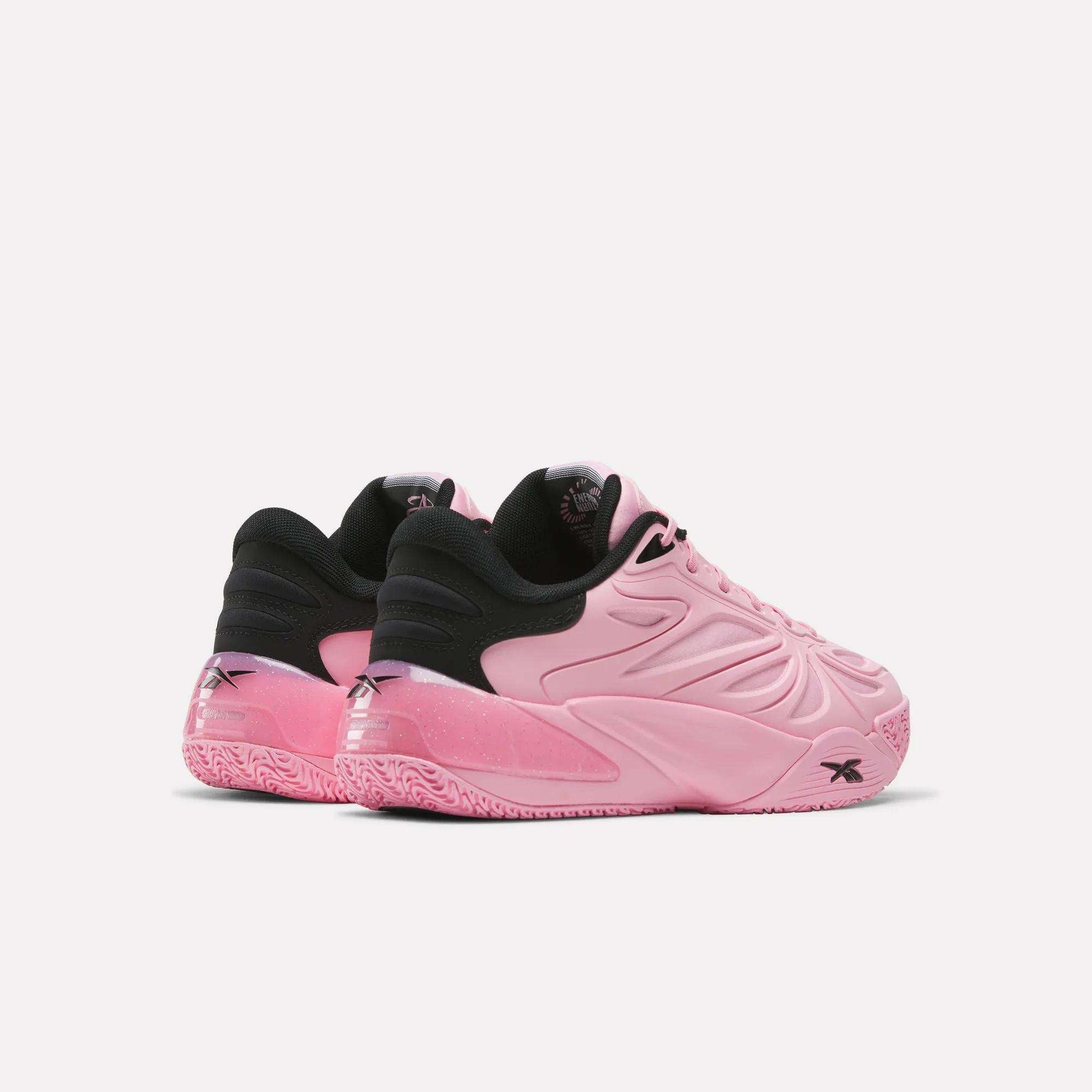 Two pink Angel Reese 1 Shoes by Reebok, featuring black inner lining and heel accents, are displayed against a plain white background. Showcasing a textured sole and wavy side patterns, these performance basketball shoes are inspired by Angel Reese and crafted to elevate your game with the advanced Reebok Energy Return System for responsive comfort on the court.