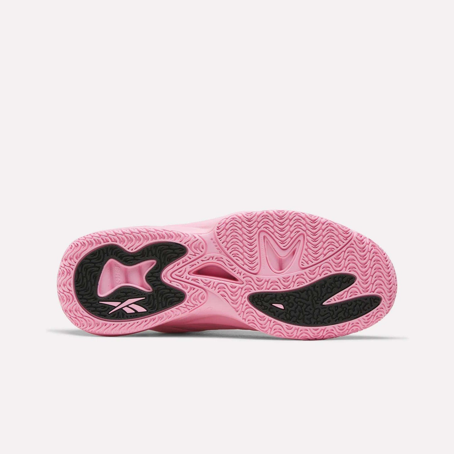 The image shows the pink sole of the Reebok Angel Reese 1 Shoes, featuring black textured rubber sections and wavy tread patterns for enhanced grip. Designed as performance basketball shoes, they also incorporate the Reebok Energy Return System to boost comfort and responsiveness on the court.