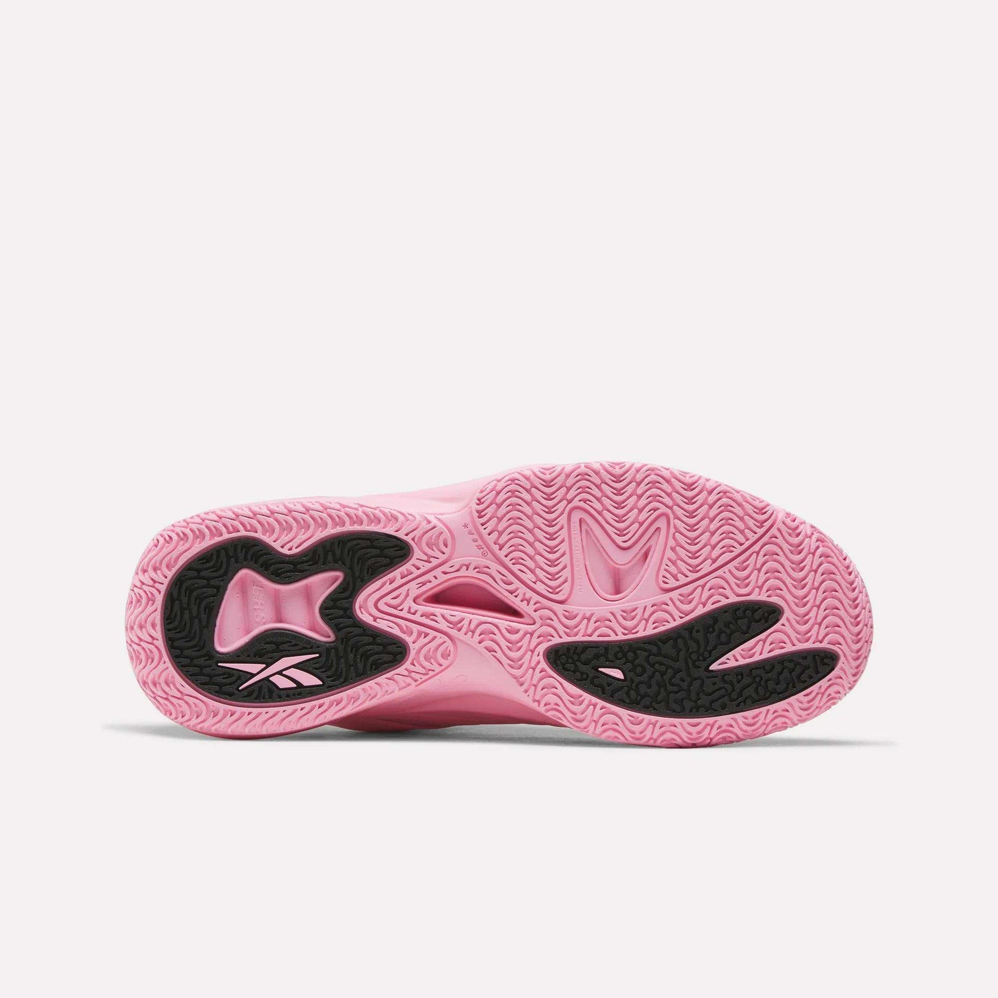 The image shows the pink sole of the Reebok Angel Reese 1 Shoes, featuring black textured rubber sections and wavy tread patterns for enhanced grip. Designed as performance basketball shoes, they also incorporate the Reebok Energy Return System to boost comfort and responsiveness on the court.