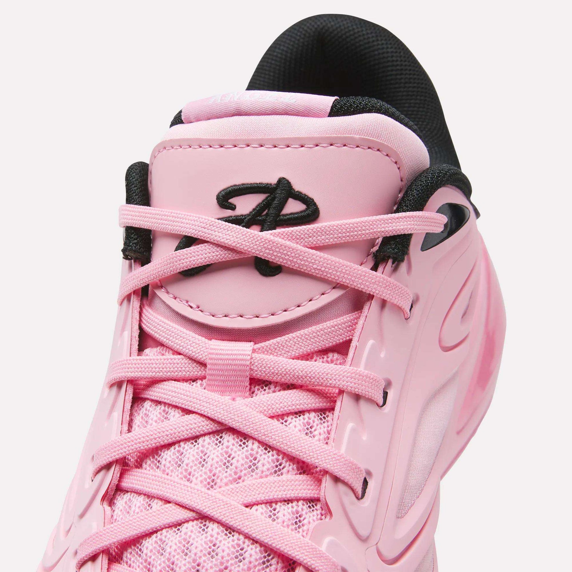 Close-up of the Reebok Angel Reese 1 Shoes in pink, featuring matching pink laces, black eyelets, and a black padded tongue with the Reebok "A" logo. Inspired by performance basketball footwear, this style is crafted with mesh and synthetic materials for enhanced comfort and support.