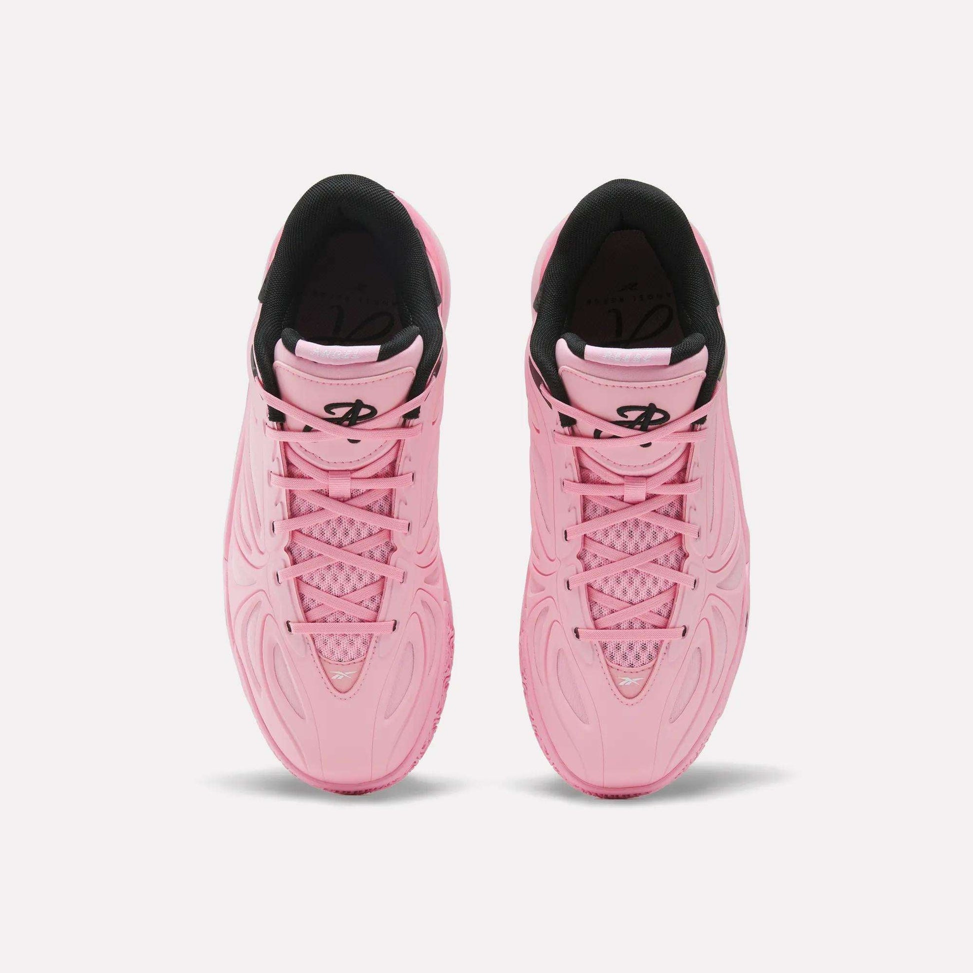 Pair of pink Angel Reese 1 athletic sneakers by Reebok with textured patterns, black lining, and a black logo on the tongue, viewed from above on a white background—these performance basketball shoes feature the Reebok Energy Return System for added comfort and support.