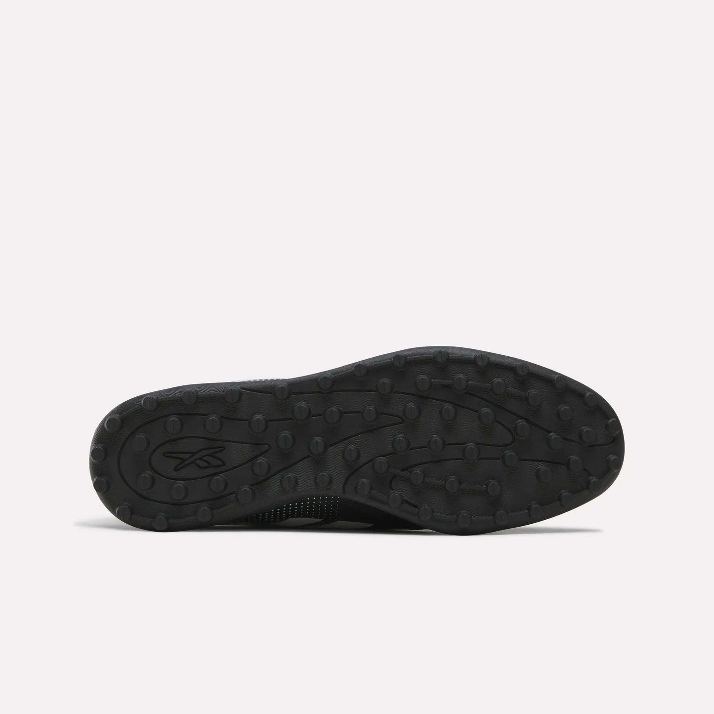 Black rubber sole featuring a textured tread pattern with small round bumps, displayed against a plain light background. Designed for the Reebok Strike Turf Soccer Shoes, this sole is perfect for soccer practice. A small Reebok logo appears on the left side of the sole.