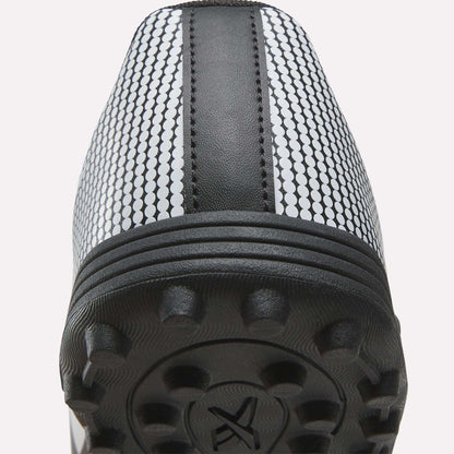 Close-up view of the heel and sole of the Reebok Strike Turf Soccer Shoes, showcasing textured rubber studs, a central black stripe, and a white upper patterned with small black circles—ideal as practice soccer shoes.