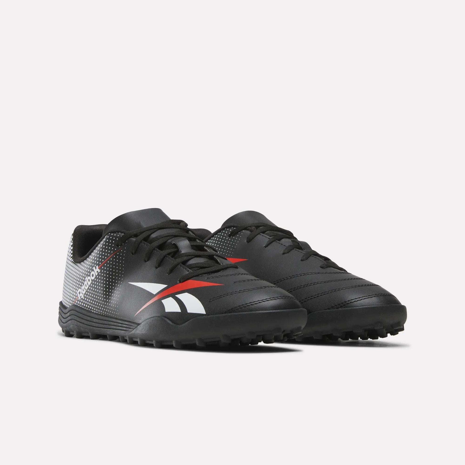 The Reebok Strike Turf Soccer Shoes are a pair of black athletic footwear accented with white and red details, featuring textured soles and the Reebok logo on the side, displayed against a plain white background.