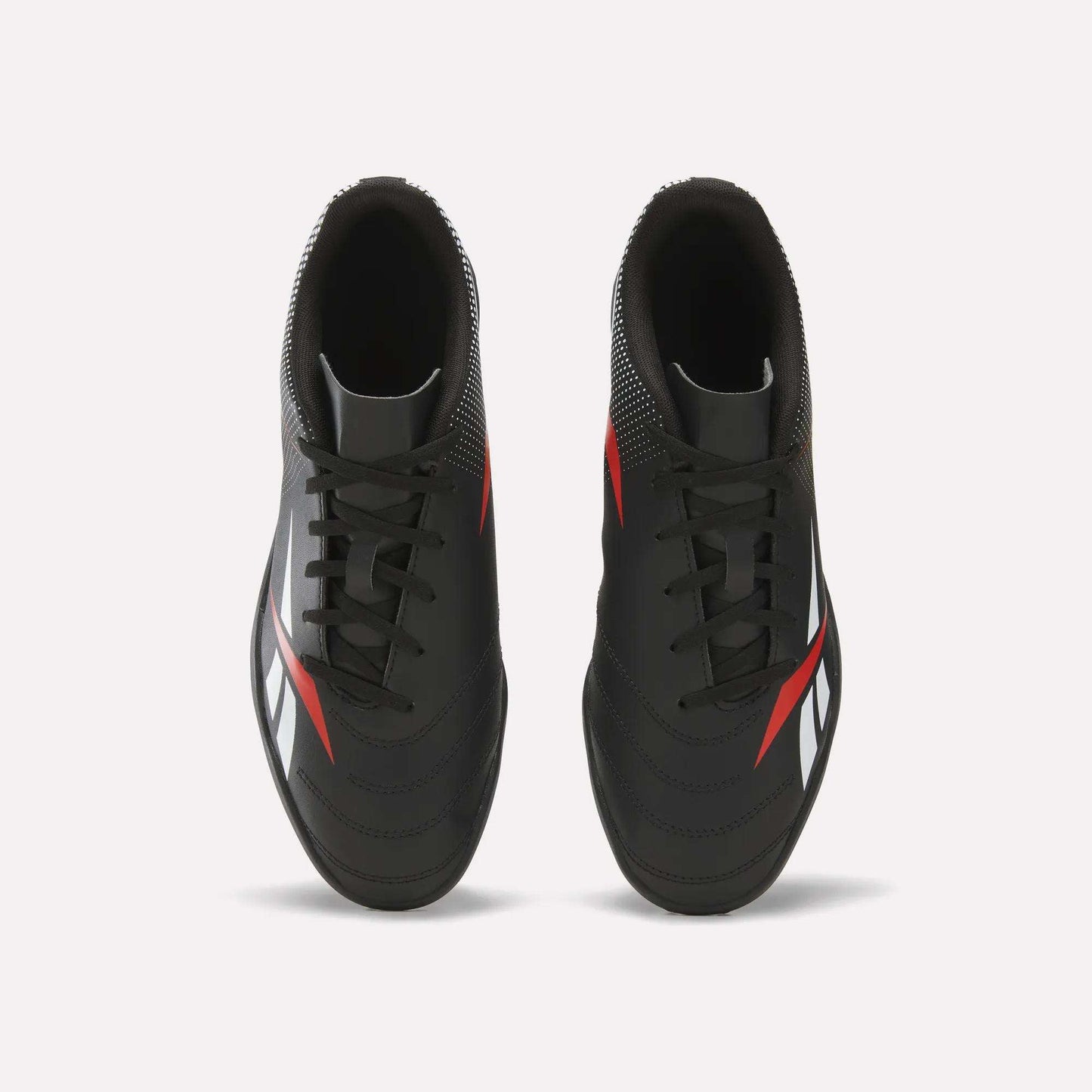 A top-down view of Reebok Strike Turf Soccer Shoes in black with red and white accents, set against a clean white background.
