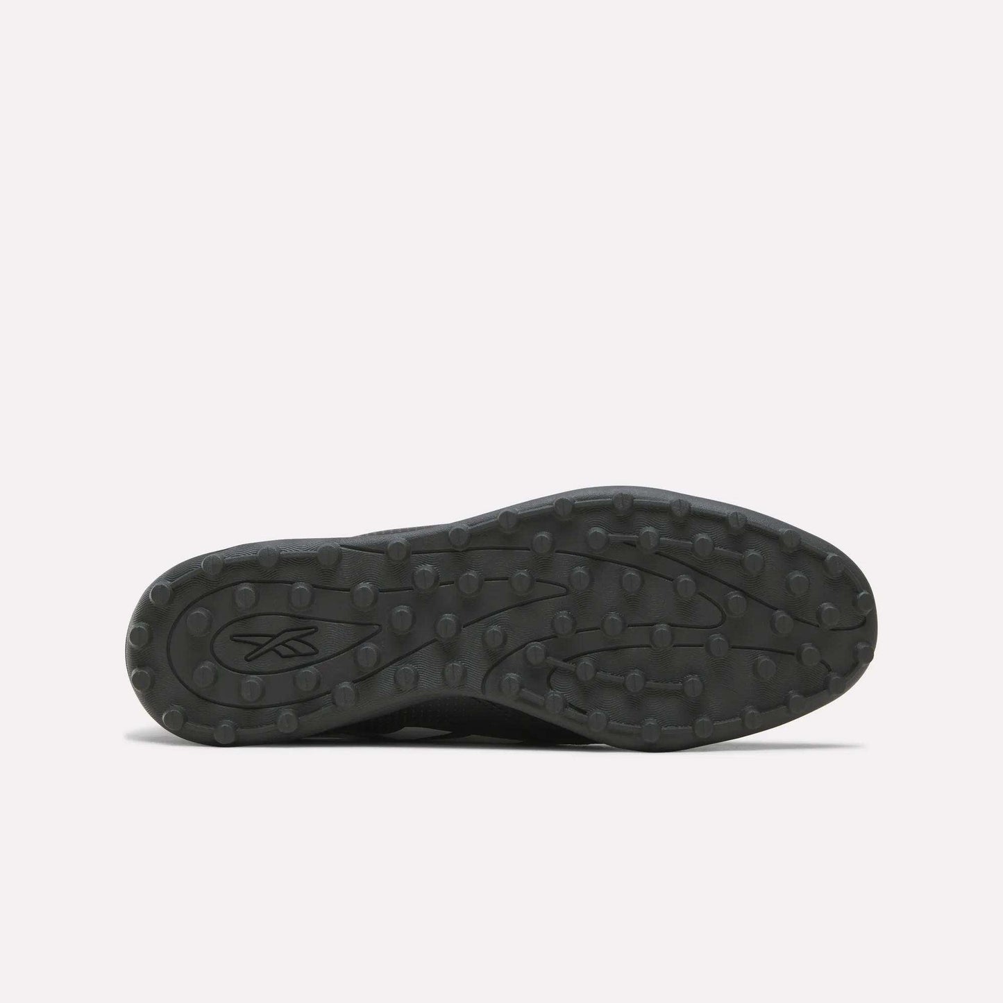 The image displays the black rubber sole of the Reebok Strike Turf Soccer Shoes, viewed from below. The sole features round traction bumps ideal for turf soccer play and practice, along with an abstract Reebok logo near the heel.