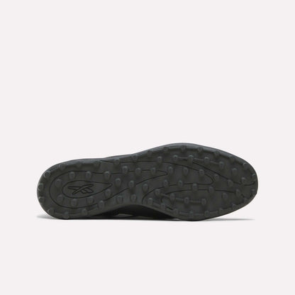 The image displays the black rubber sole of the Reebok Strike Turf Soccer Shoes, viewed from below. The sole features round traction bumps ideal for turf soccer play and practice, along with an abstract Reebok logo near the heel.